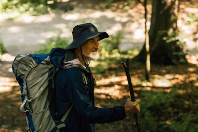Side view of young woman standing in forest