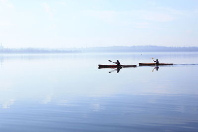 Men on boat in lake against sky