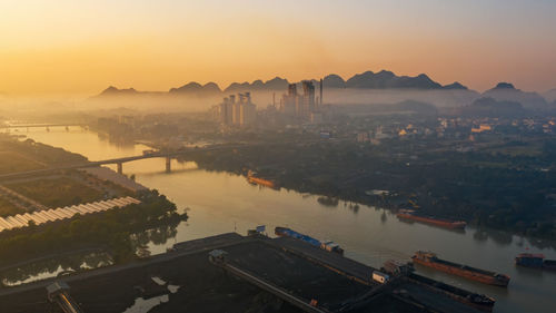High angle view of river and cityscape against sky during sunset