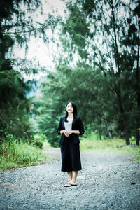 Full length of woman standing in forest