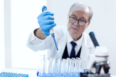 Portrait of scientist holding dental equipment against white background
