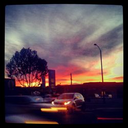 Traffic on road against cloudy sky at sunset