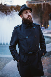 Young man looking away while standing outdoors