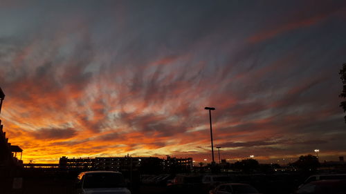 Vehicles on road against dramatic sky during sunset