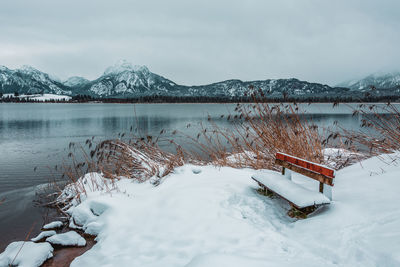 Scenic view of lake by snowcapped mountains against sky