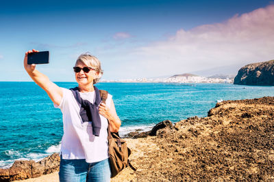 Young man photographing while standing on beach