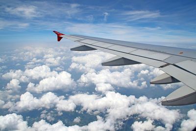 Cropped image of airplane flying over cloudscape against sky