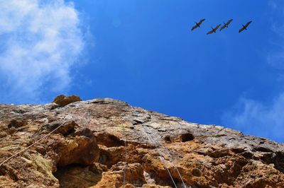Low angle view of rocky mountain against blue sky