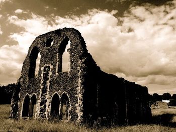 Old ruins on field against cloudy sky