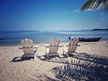 Chairs on beach against sky