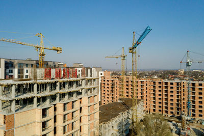 Construction site by buildings against clear blue sky