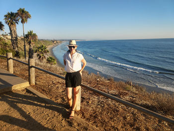 Full length of woman standing against railing and sea