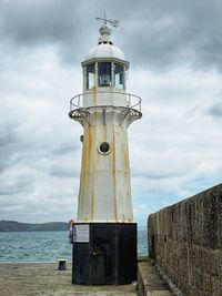 Lighthouse by sea against sky