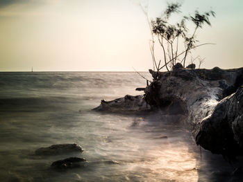 Rock formation on beach against sky during sunset