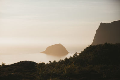 Rocks by sea against sky during sunset
