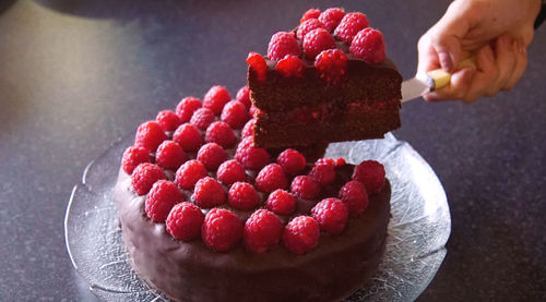 Cropped image of woman holding cake slice with knife