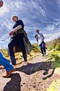Low angle view of friends walking on mountain against blue sky