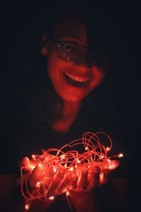 Close-up of young woman with light painting against black background