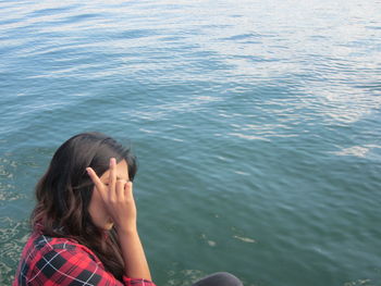 Woman showing peace sign at lakeshore