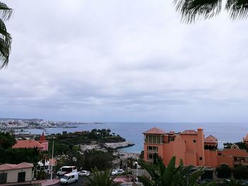 Houses in town by sea against sky