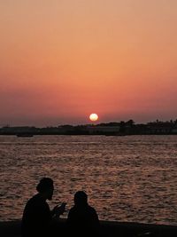 Silhouette hot air balloon on sea against romantic sky at sunset