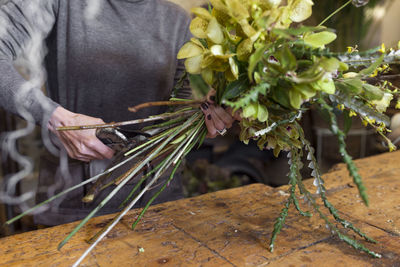 Cropped image of unrecognisable woman using scissors at flower shop