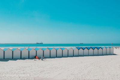 Deck chairs on beach against clear blue sky