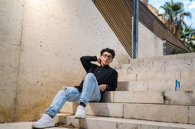 Young transgender person looking away while sitting on stairs outdoors.
