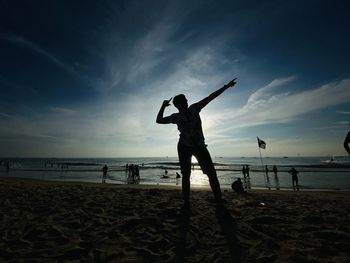 Silhouette people at beach against sky