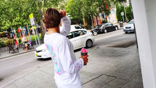 Rear view of woman standing on street in city