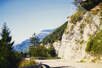 Road leading towards mountains against clear blue sky