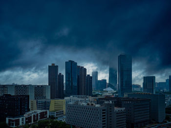 Skyscrapers in city against cloudy sky