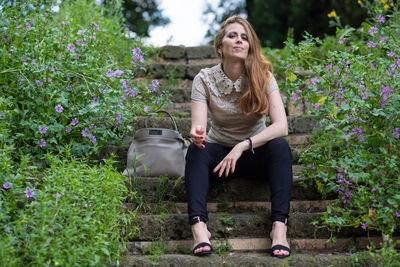 Full length of woman sitting by plants
