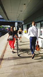 Rear view of people walking on road in city