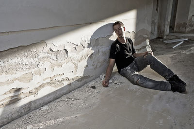 Full length of woman sitting on floor against wall