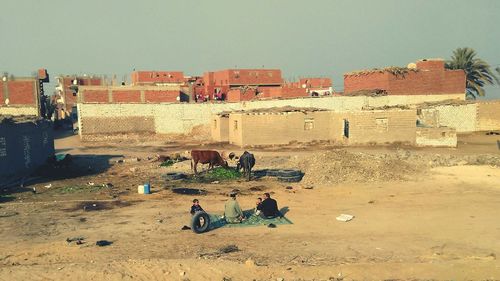 People sitting on fort against clear sky