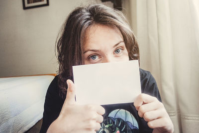 Portrait of woman holding paper at home