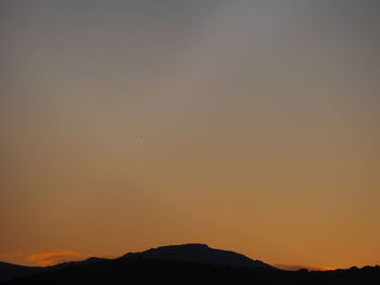 Scenic view of silhouette mountains against orange sky