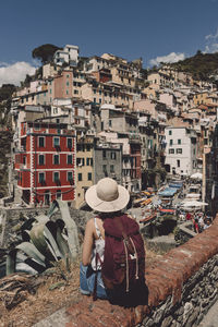 Rear view of female tourist with backpack wearing hat while looking at cityscape during sunny day