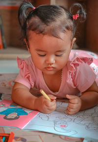 Portrait of cute girl drawing on paper at home