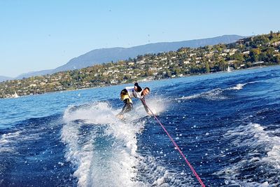 People skiing on mountain against clear blue sky