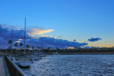 Sailboats moored in sea against blue sky