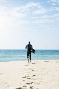 Rear view of man on beach against sky