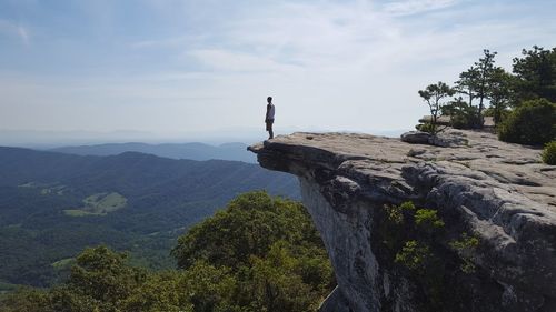 Man standing on cliff against sky