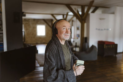 Portrait of senior man listening to music through headphones at home