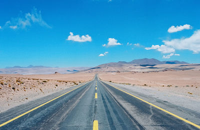 Road leading towards mountain against sky