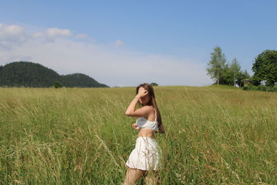 Rear view of woman standing on field against sky