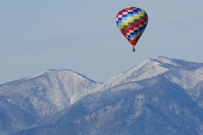 Vivid colored hot air balloon flying in snowy mountains against sky