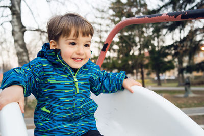 Cute boy playing on slide at playground