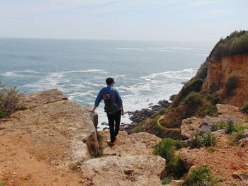 Rear view of man looking at sea against sky